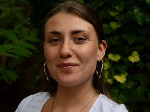 Man singing into a microphone with his eyes closed and playing a guitar.