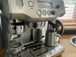 Stainless steel home espresso machine sitting on a kitchen countertop.