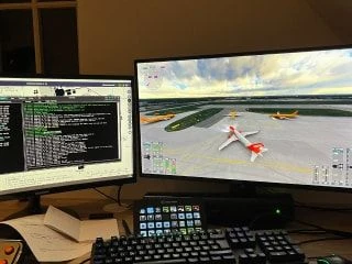 Dual-monitor computer setup displaying a flight simulator and aviation control software.